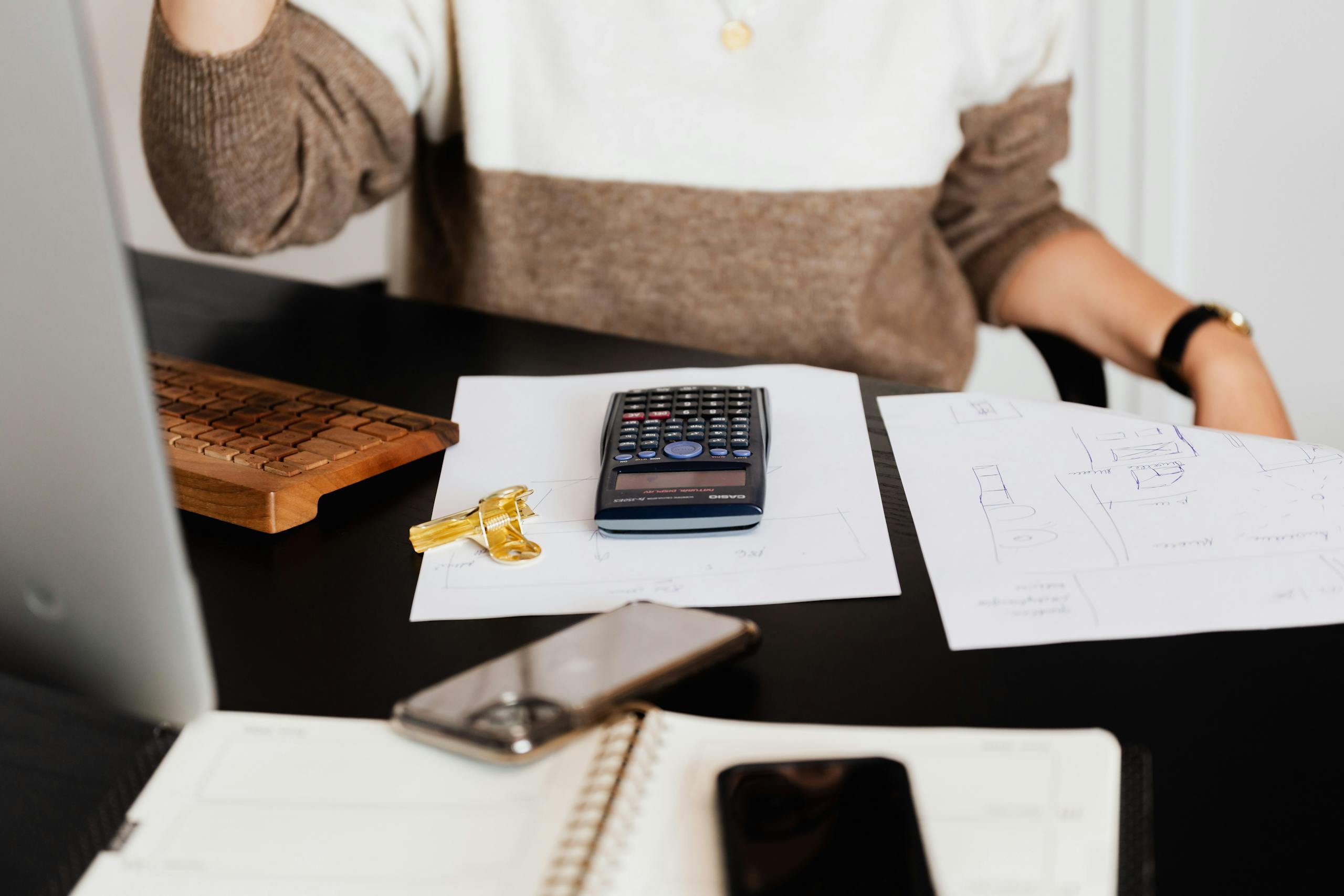 A business desk setup with a calculator, papers, and a keyboard, reflecting a work environment.